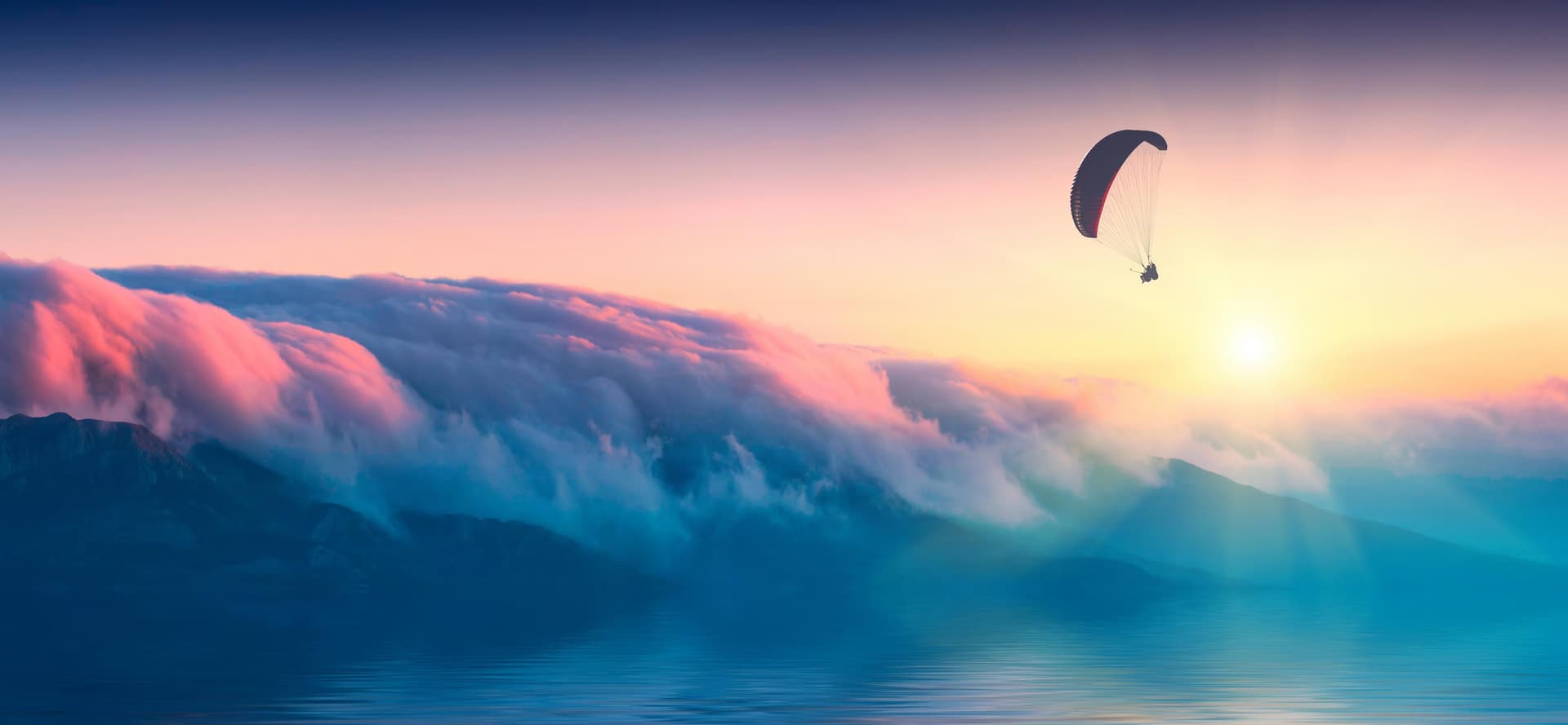 Rainbow clouds with person paragliding on the right hand side